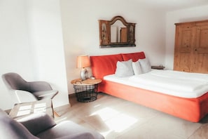 A bedroom with a large bed, a wooden wardrobe, a bedside table with a lamp, and a chair. - House Luna - Apartment Luna 7 (Schwangau)