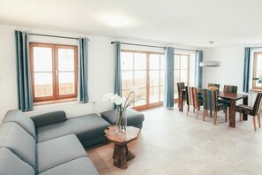 Ein modernes Wohnzimmer mit einem grauen Sofa, einem Couchtisch mit einer Vase und einem Essbereich mit Tisch und Stühlen.