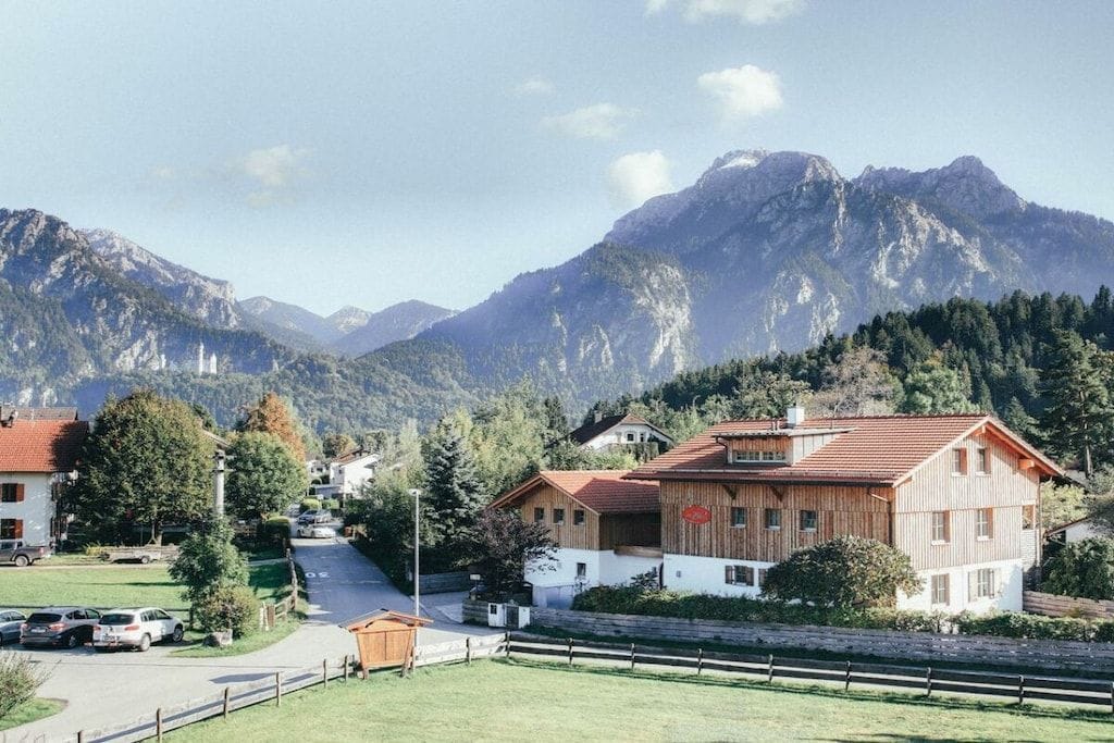 A mountain village with traditional wooden houses, a clear road, and a view of the surrounding mountains.