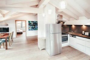A modern kitchen with a stainless steel refrigerator, a dining area with a wooden table, and a painting on the wall. - Luna Blanca - Apartment 3 (Schwangau)