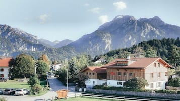 Ein Bergdorf mit traditionellen Holzhäusern, einer klaren Straße und Blick auf die umliegenden Berge.