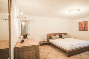 Ein Schlafzimmer mit einem hölzernen Bett, Nachttischen, einem Spiegel und einer Deckenleuchte.
