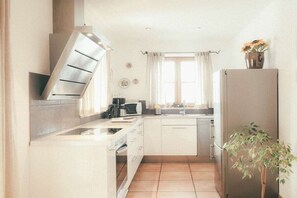 A compact kitchen with a microwave, stove, and refrigerator. - Luna Mia Apartment 3 (Schwangau)