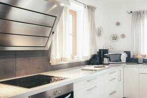 A modern kitchen with a stainless steel range hood, a microwave, and a coffee maker. - Luna Mia Apartment 3 (Schwangau)