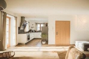 Eine moderne Küche mit einer zentralen Kochinsel, einem Essbereich mit einer Couch und einer Holztür.