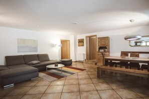 A living room with a sofa, coffee table, and a dining area with a bench. - Luna Mia Apartment 3 (Schwangau)