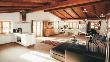A spacious living area with a kitchen, dining table, and a cozy seating area.