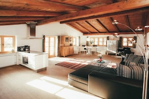 A spacious living area with a kitchen, dining table, and a cozy seating area. - Luna Mia Apartment 4 (Schwangau)