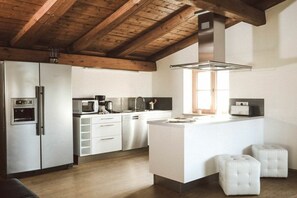 A modern kitchen with stainless steel appliances, wooden beams, and a central island with stools. - Luna Mia Apartment 4 (Schwangau)
