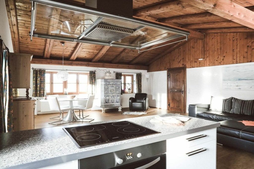 A kitchen with a modern stove, a dining area with a table and chairs, and a living area with a sofa.