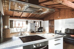 A kitchen with a modern stove, a dining area with a table and chairs, and a living area with a sofa. - Luna Mia Apartment 4 (Schwangau)