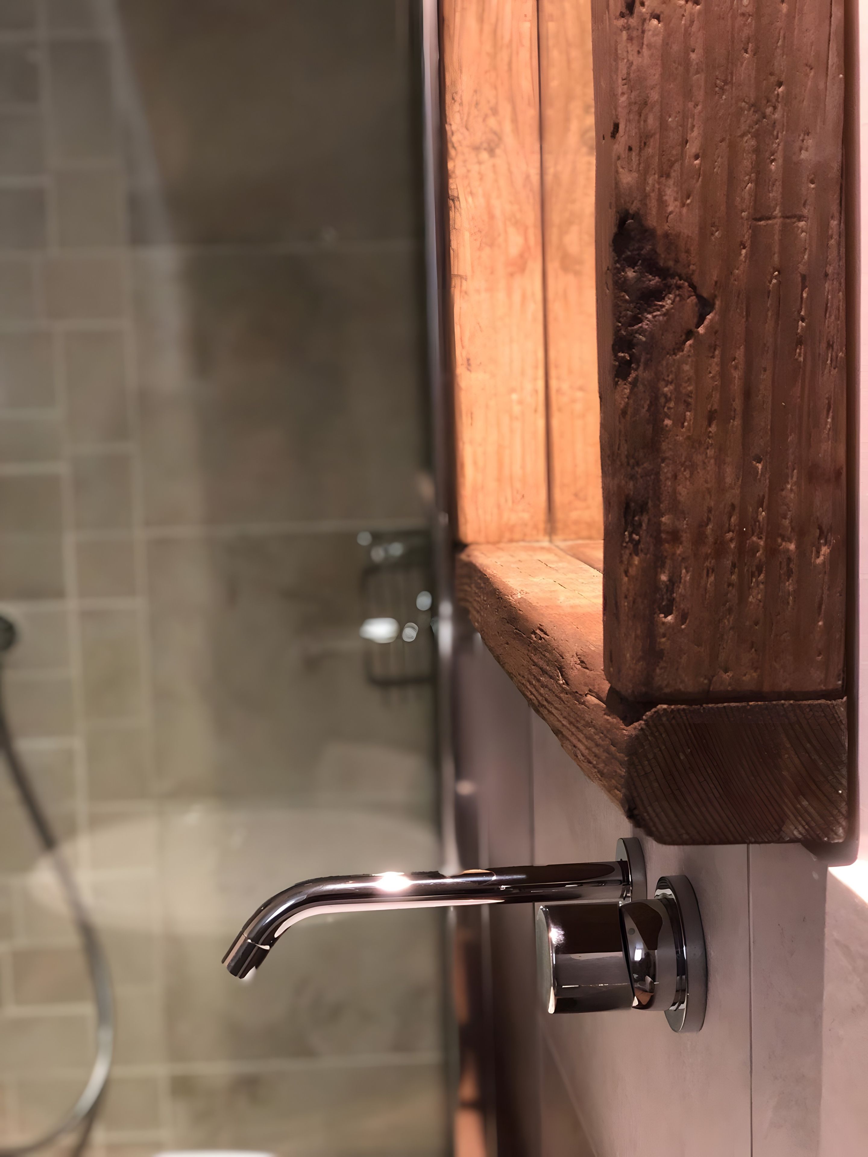 Un bagno con un mobile lavabo in legno, cabina doccia in vetro e rubinetteria cromata.
