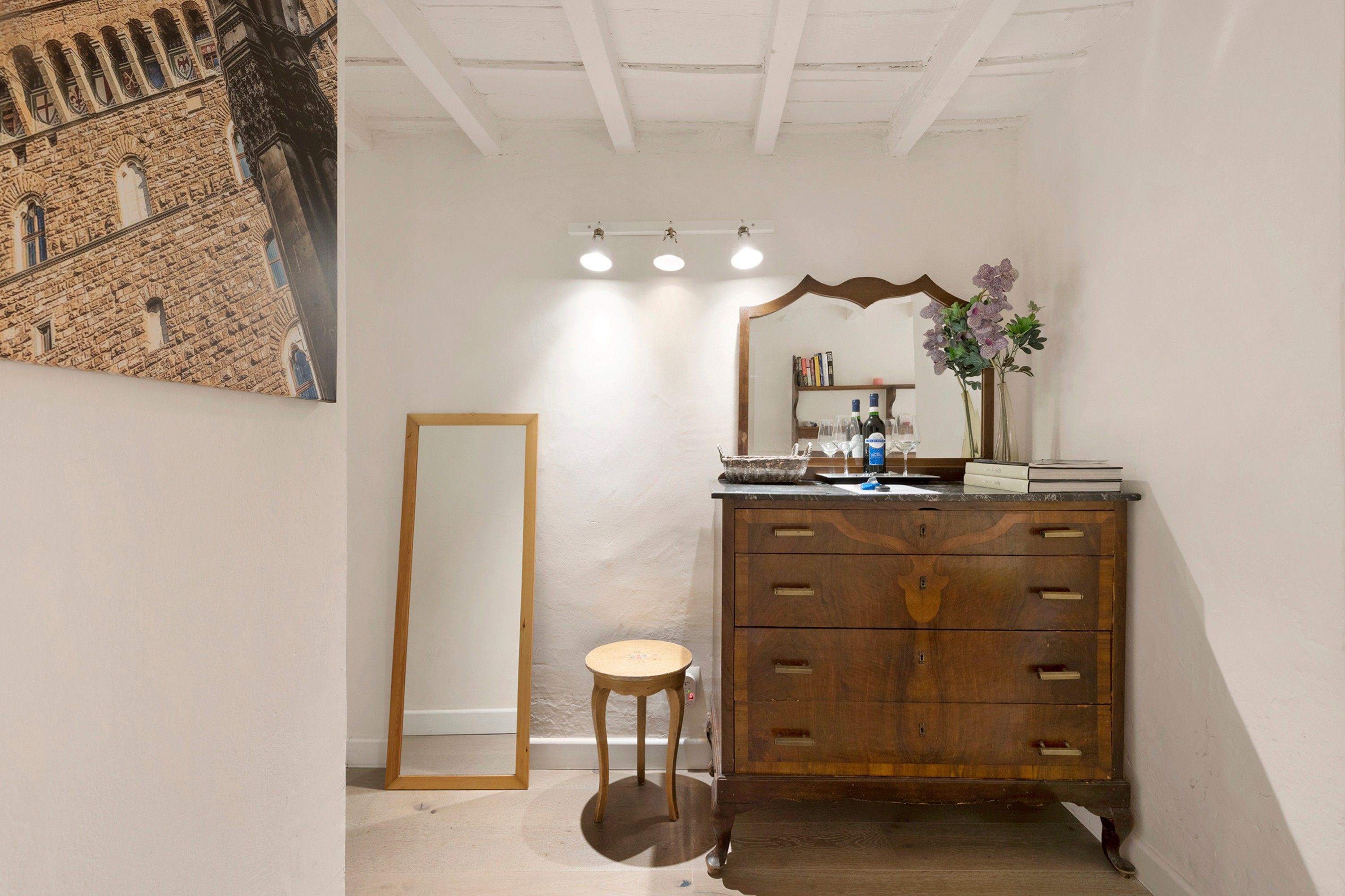 Une salle de bain avec un meuble-lavabo en bois, un miroir et un petit tabouret.