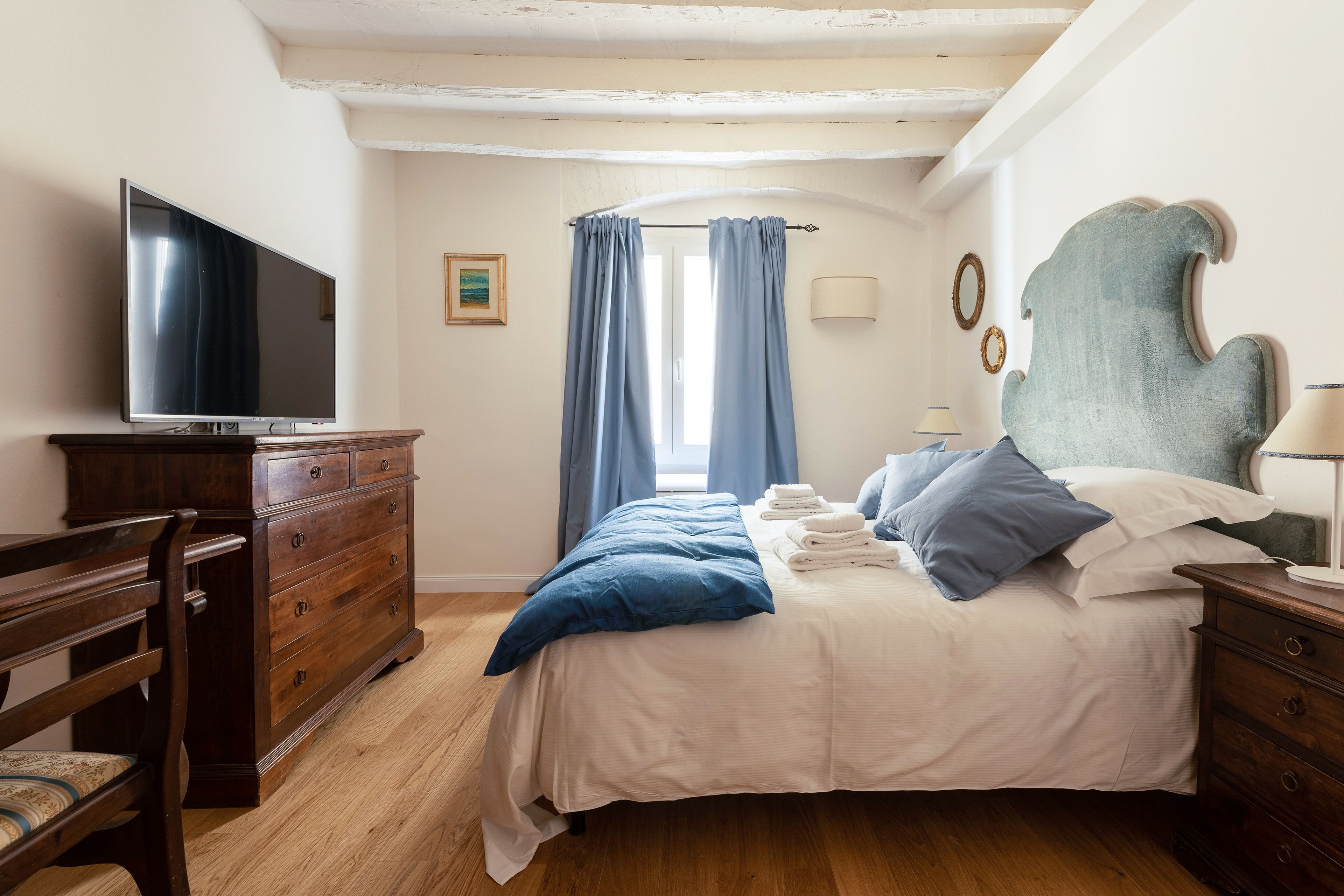 Ein Schlafzimmer mit einem Bett, einem Fernseher, einem Schminktisch und einem Sessel.