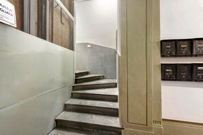 Un escalier avec une paroi en treillis métallique d’un côté et une rangée d’armoires de rangement noires de l’autre.