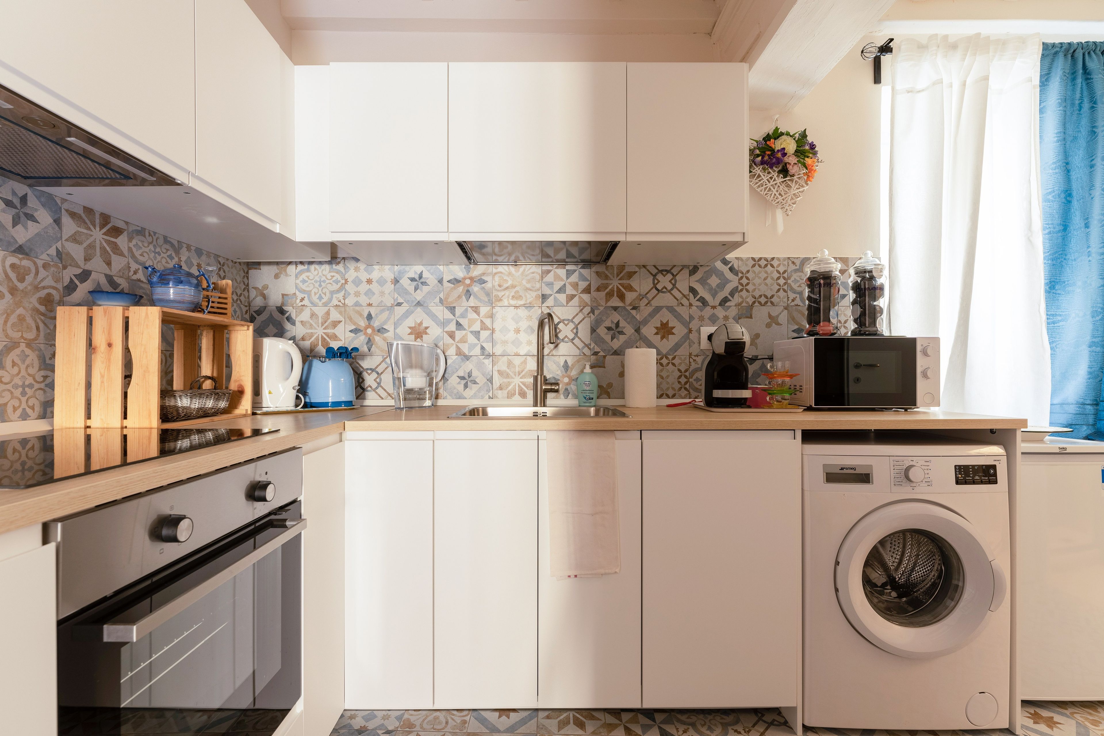 Een moderne keuken met een wasmachine, een magnetron en een spoelbak.