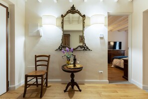 A hallway with a wooden chair, a table with a vase of flowers, and a mirror with a decorative frame. - Holiday Home 'Anna's House Ponte Vecchio' with Wi-Fi (Firenze)