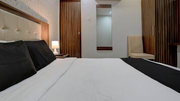 A hotel room with a large bed, a bedside table with a lamp, a chair, and a wardrobe.