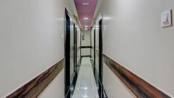 A hotel corridor with a marble floor, wooden paneling, and a pink ceiling.