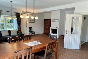 A dining area with a wooden table, chairs, and a fireplace. - Holiday apartment in Sylt with swimming pool (Sylt)