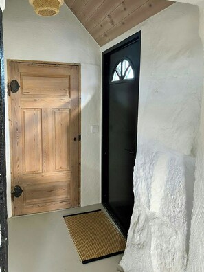 Eine Holztür mit einer strukturierten Wand und einem schwarzen Türrahmen.