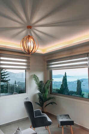 Ein modernes Zimmer mit großem Fenster, einer Topfpflanze und einer außergewöhnlichen Deckenleuchte.