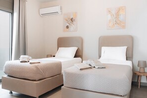 Ein Hotelzimmer mit zwei Betten, einem Nachttisch, einer Klimaanlage und Bildern an den Wänden.
