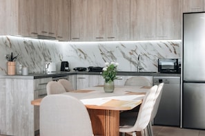 Eine moderne Küche mit Marmorfliesenspiegel, Backofen und Edelstahl-Kühlschrank.