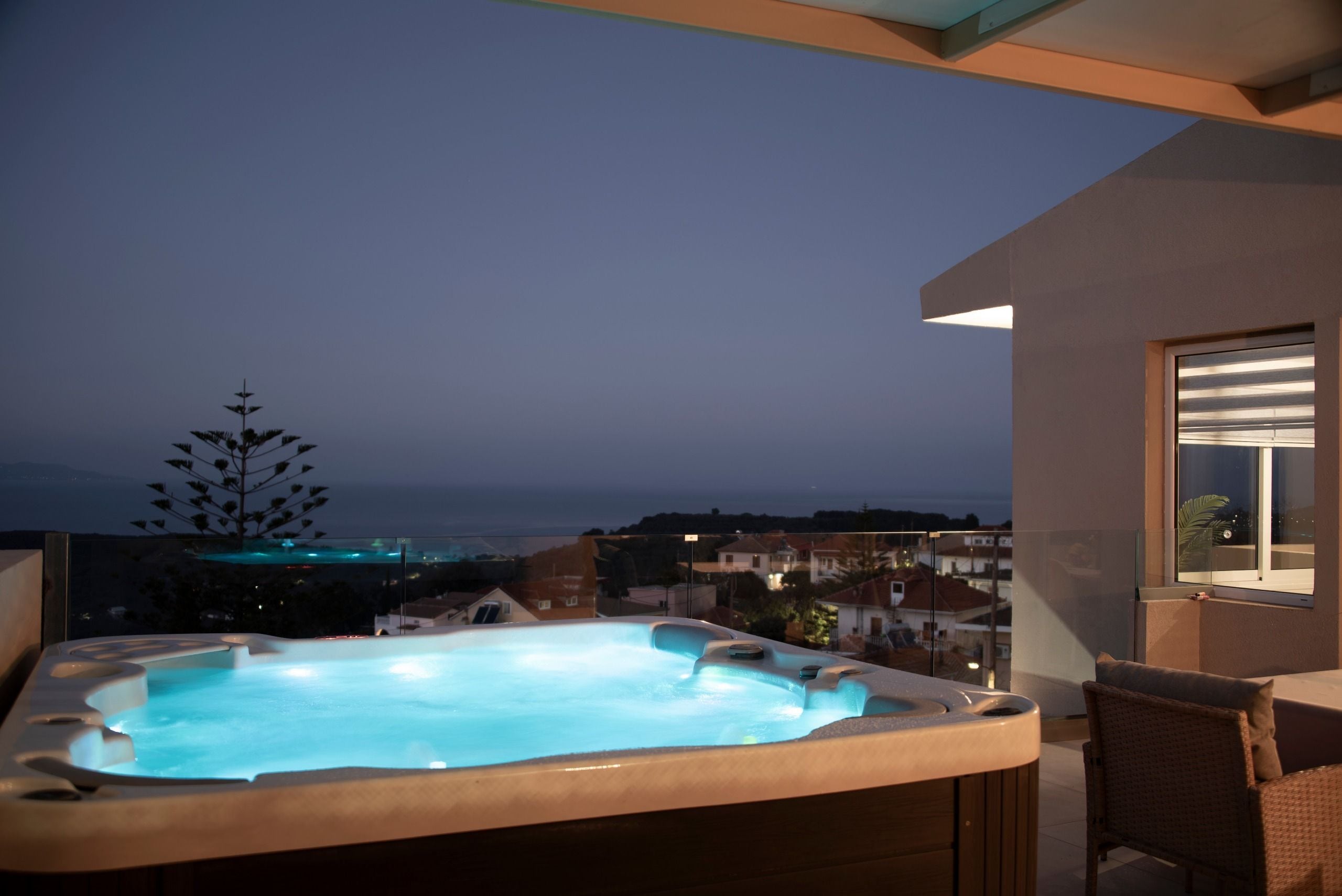 A hot tub on a balcony with a view of the city at dusk.