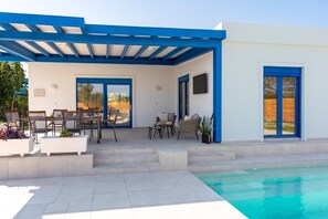 A covered outdoor area with a pool, a dining table, and chairs. - Serenity Villa Thalassa (Rhodes)