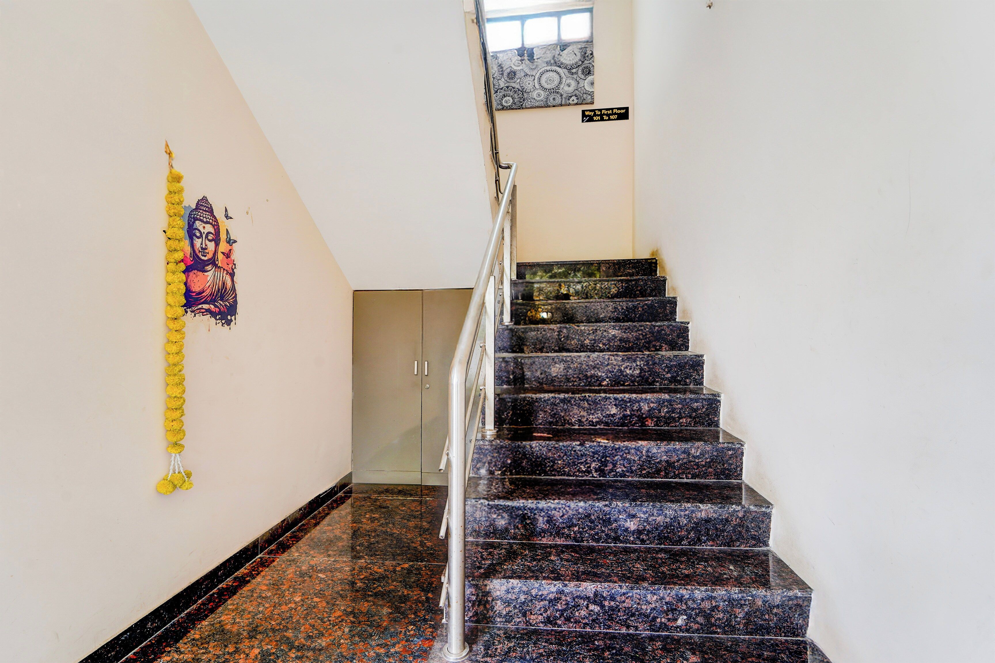 A staircase with a handrail, a wall with a decorative hanging, and a sign indicating the floor level.