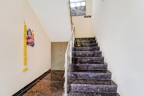 Una escalera con barandilla, una pared con un adorno colgante y un cartel que indica el nivel del piso.