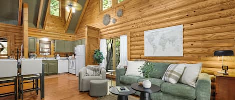 A spacious log cabin interior with a dining area, kitchen, and living room.