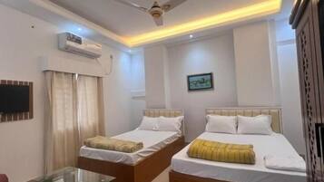 A hotel room with two beds, a ceiling fan, a flat-screen TV, and a red rug.