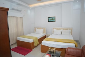 A hotel room with two single beds, a small table, a chair, and a red rug.