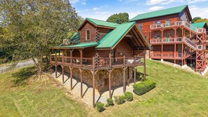 A wooden cabin with a balcony and a stone foundation. - Sleeps 6, Family Cabin, Hot Tub, Community Pool, Playground, 6 Mi to Dollywood (Pigeon Forge)