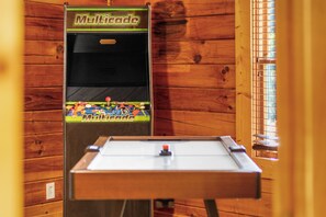 A foosball table with a Multicade logo, set against a wooden wall with a window to the right. - Sleeps 6, Family Cabin, Hot Tub, Community Pool, Playground, 6 Mi to Dollywood (Pigeon Forge)