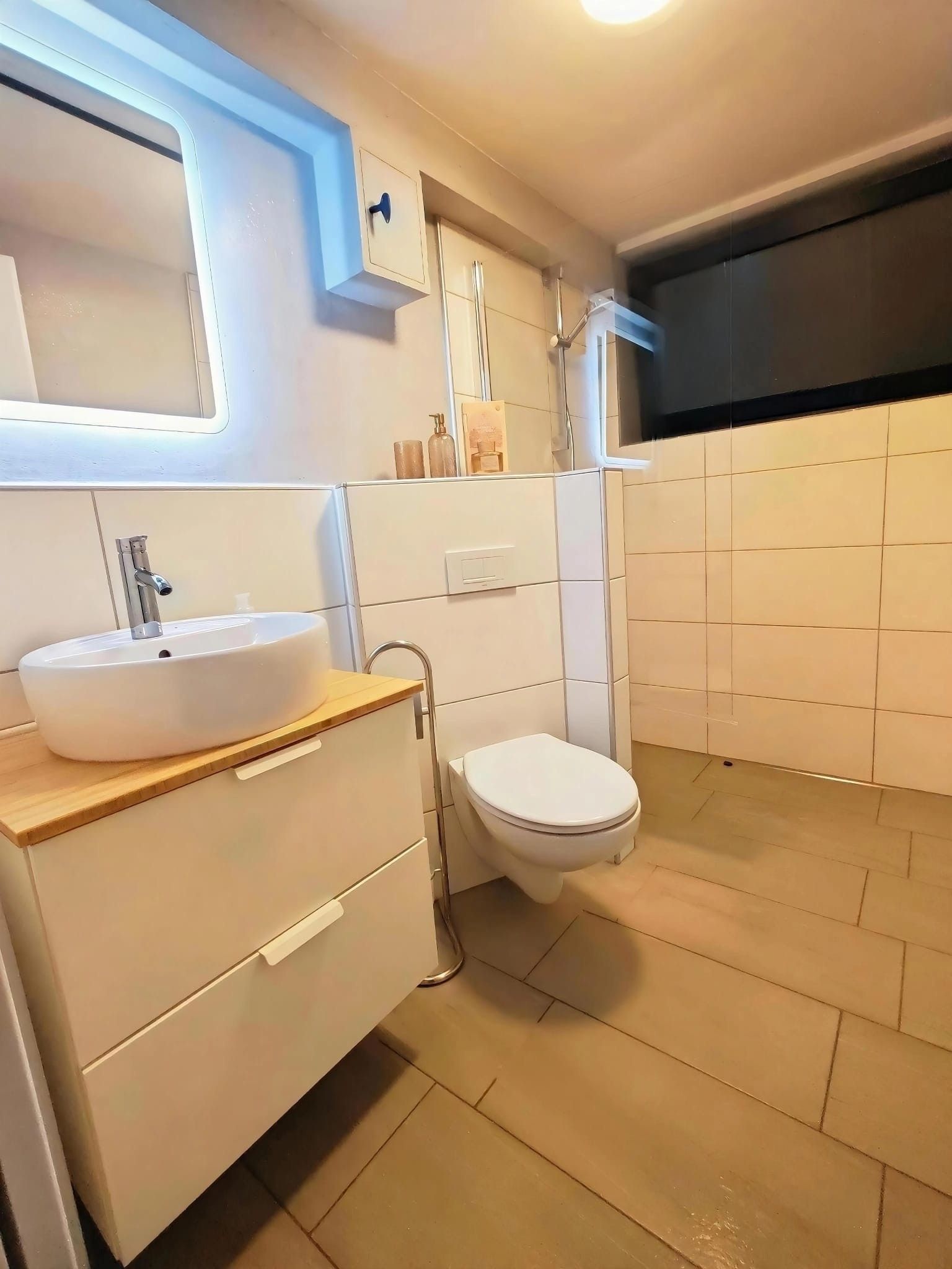 A modern bathroom with a white sink, a toilet, and a shower.