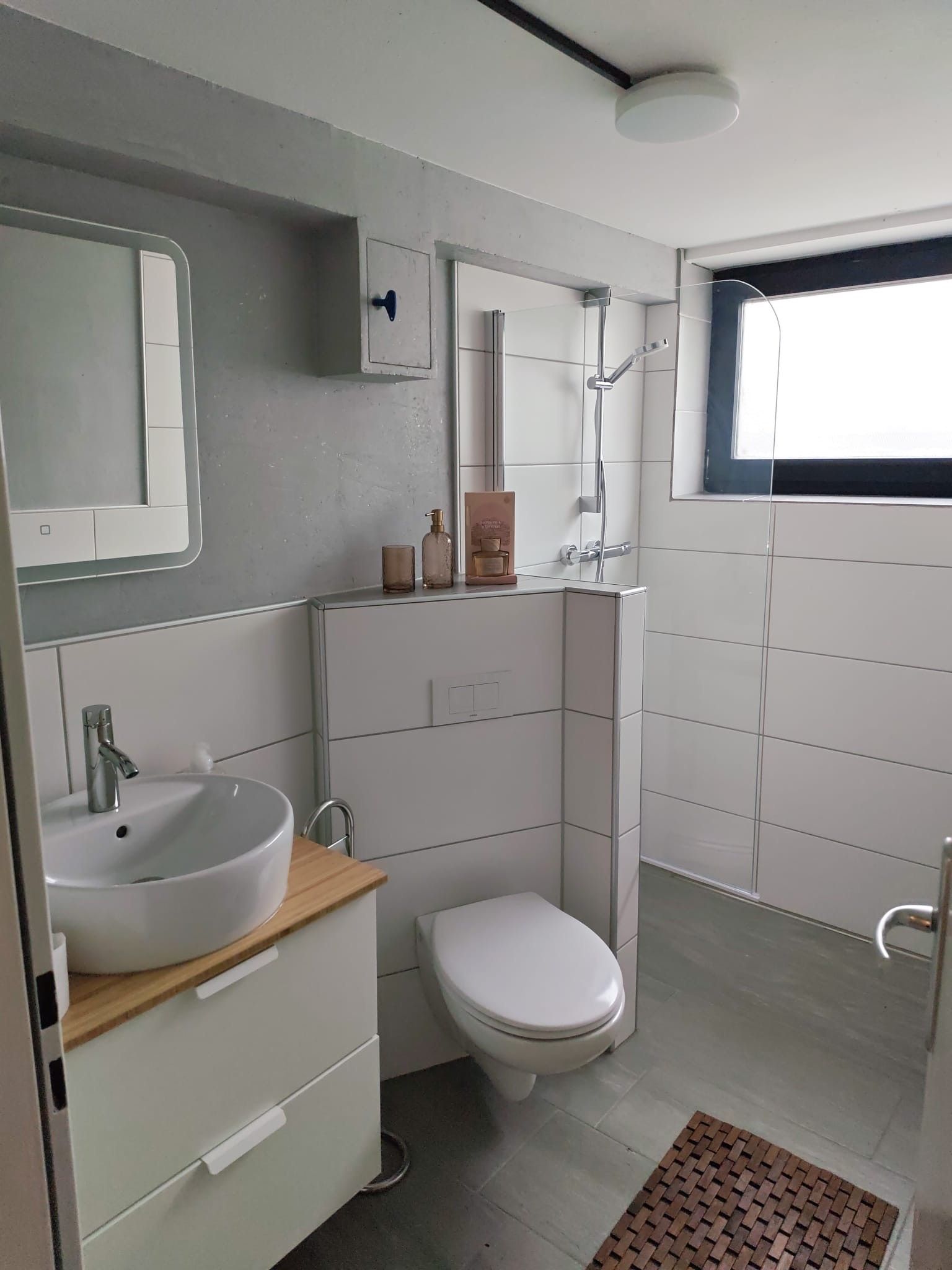 A modern bathroom with a white sink, toilet, and shower.