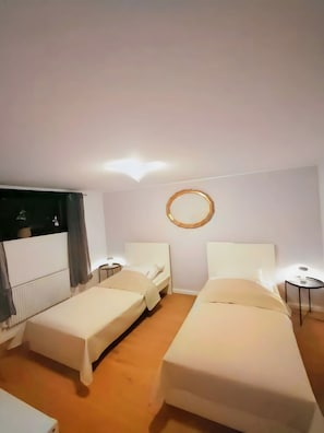 A hotel room with two beds, a round mirror on the wall, and a small table by each bed. - Apartment 'Rosdorf Lodge - Nahe Göttingen' with Wi-Fi (Rosdorf)
