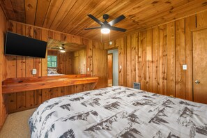 A wooden cabin interior with a bed, a mounted TV, a ceiling fan, and a window with blinds. - Sleeps 6, Mountain View Hot Tub, Sunset Deck, Single Level, Fireplace (Sevierville)