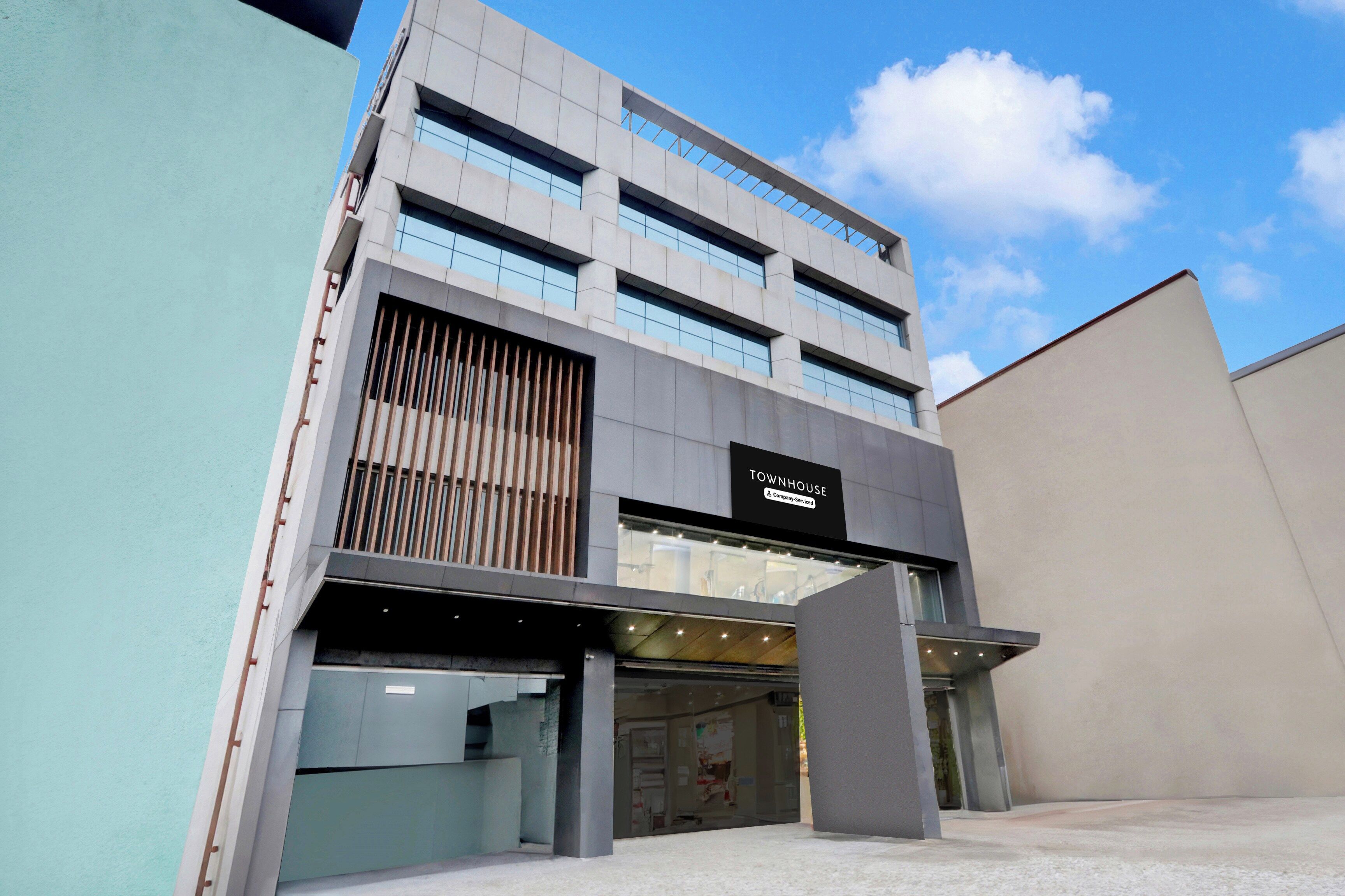 A modern building with a sign reading 'TOWNHOUSE' and a company-serviced label.