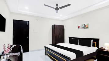 A bedroom with a bed, a wardrobe, a desk with a chair, and a ceiling fan.