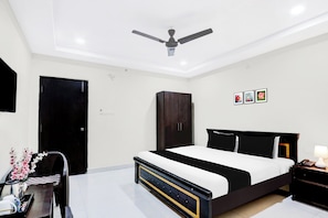 A bedroom with a bed, a wardrobe, a desk with a chair, and a ceiling fan. - Townhouse Daba Garden Road (Visakhapatnam)