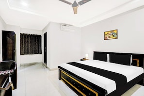 A hotel room with a bed, a chair, an air conditioning unit, a painting, and a ceiling fan. - Townhouse Daba Garden Road (Visakhapatnam)