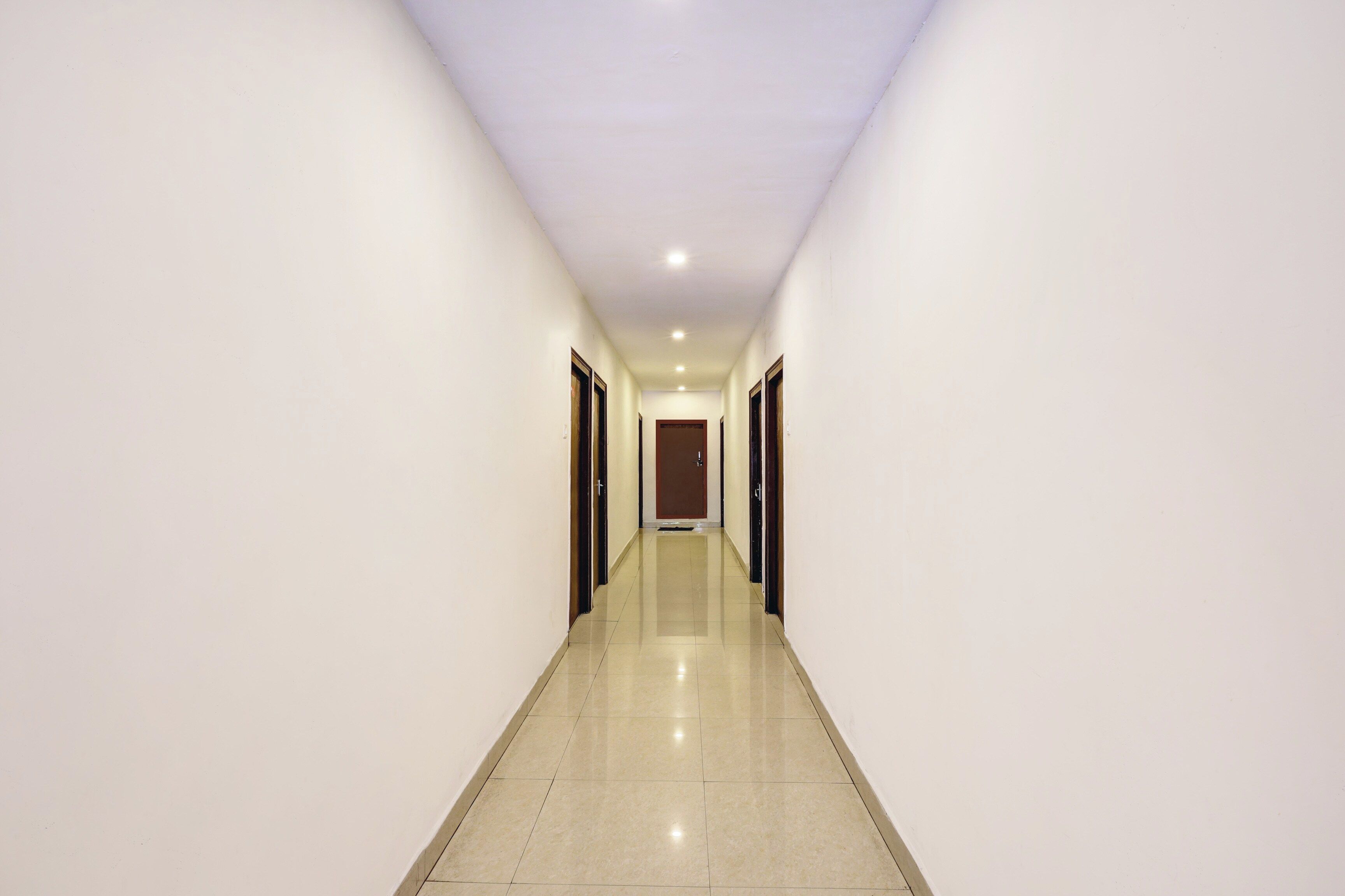 A long, narrow hallway with a shiny tiled floor and white walls.