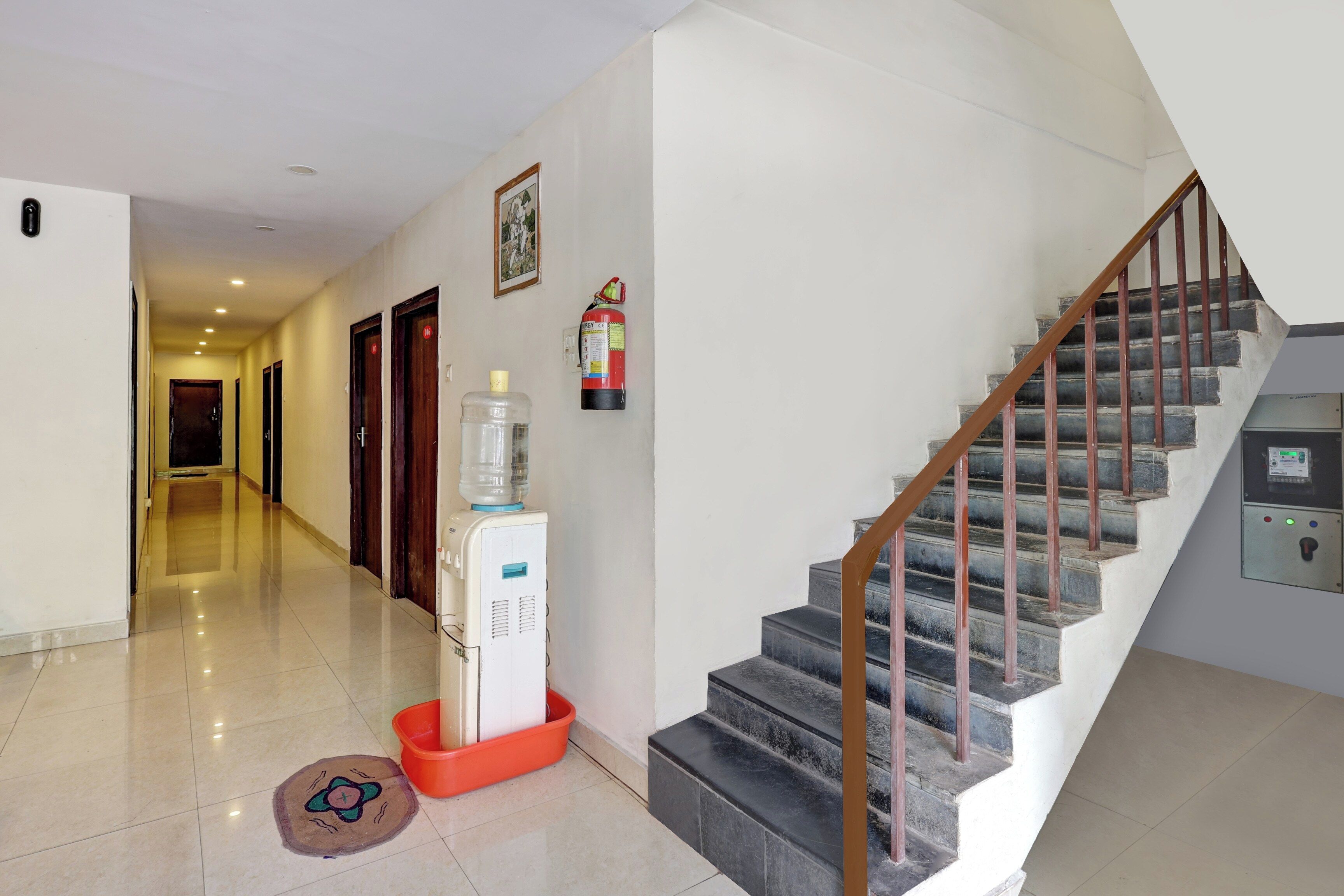 A hotel hallway with a water dispenser, a fire extinguisher, and a staircase.