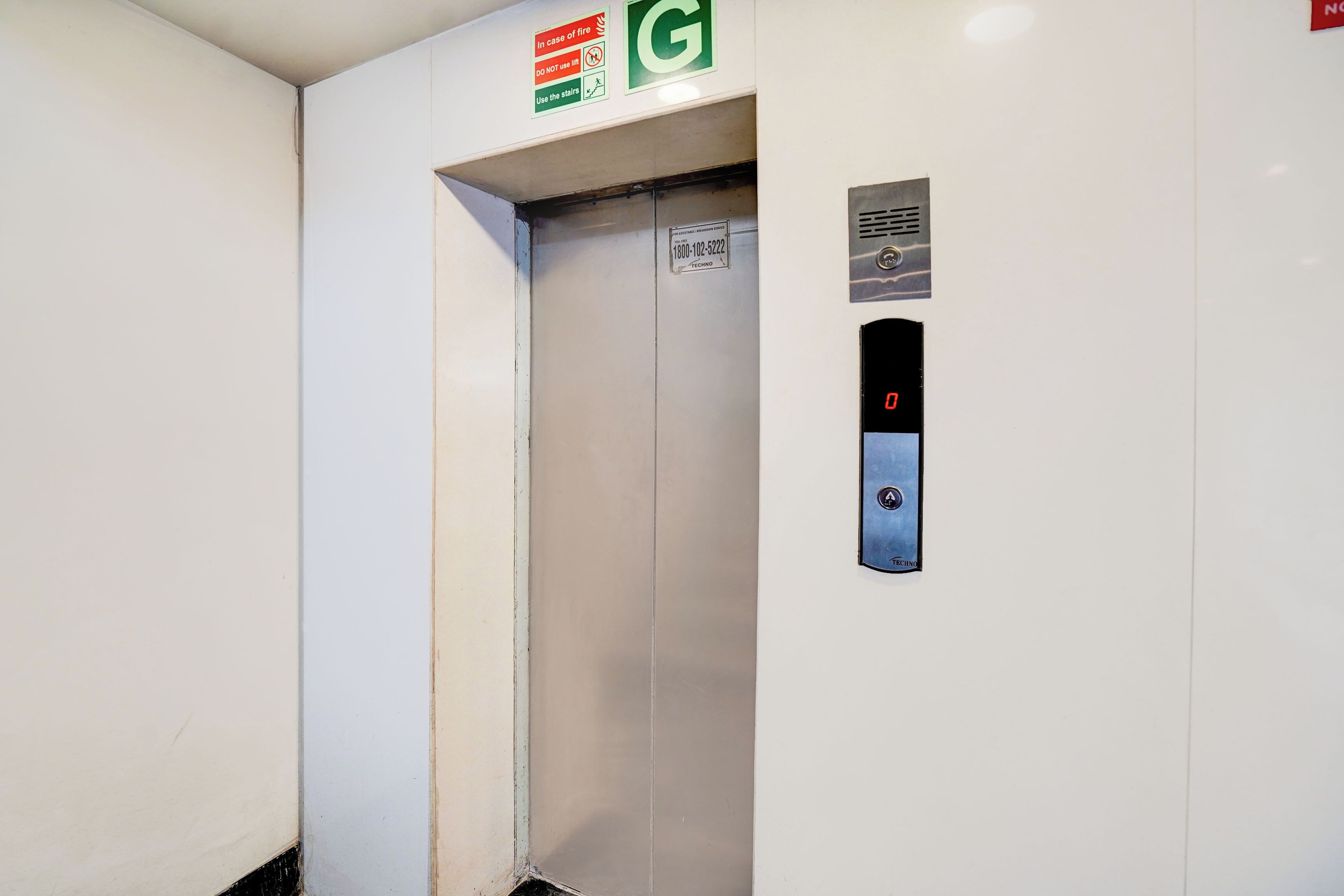 An elevator with a control panel, emergency instructions, and a phone number for assistance.