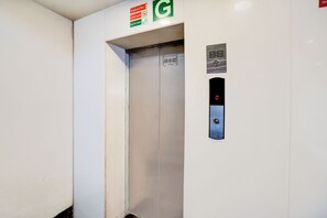 Un ascensor con panel de control, instrucciones de emergencia y un número de teléfono para asistencia.