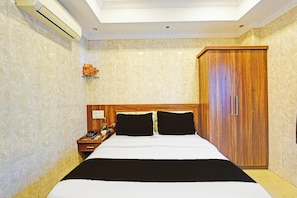 A hotel room with a bed, a nightstand, a telephone, a flower vase, and a wardrobe. - Hotel O Triplicane (Chennai)